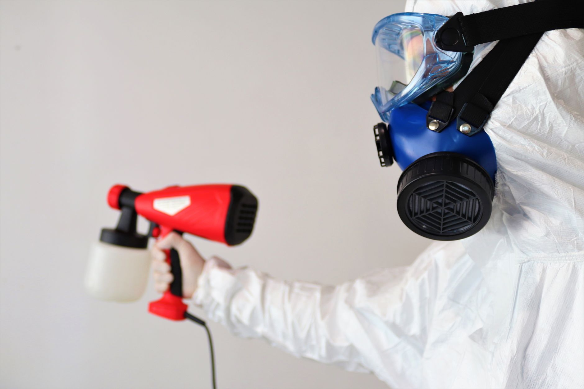 A certified mold remediation technician in full PPE, carefully inspecting a damp attic space in a Richardson home with a flashlight.