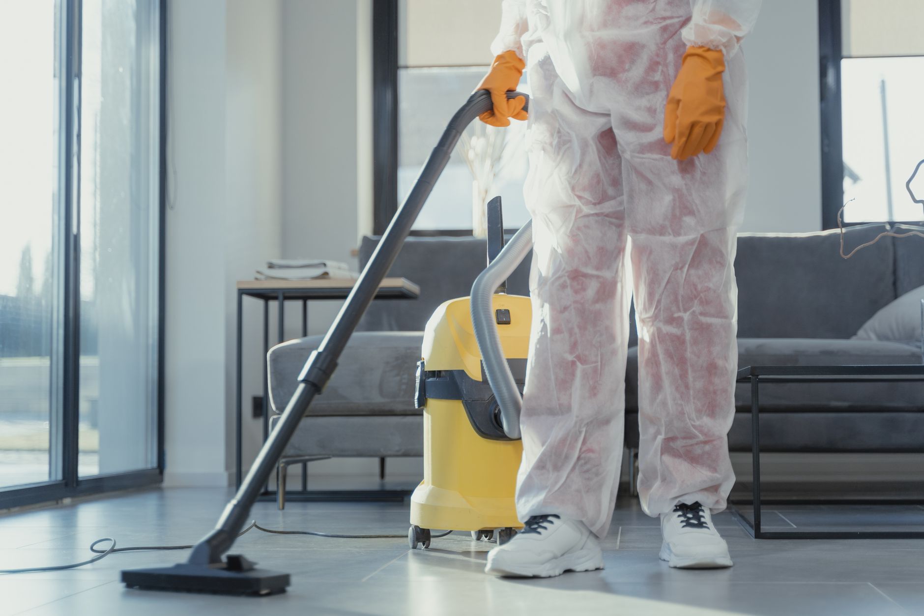 A certified mold remediation technician in full PPE explaining the process to a homeowner in a clean, post-remediation room in McKinney.